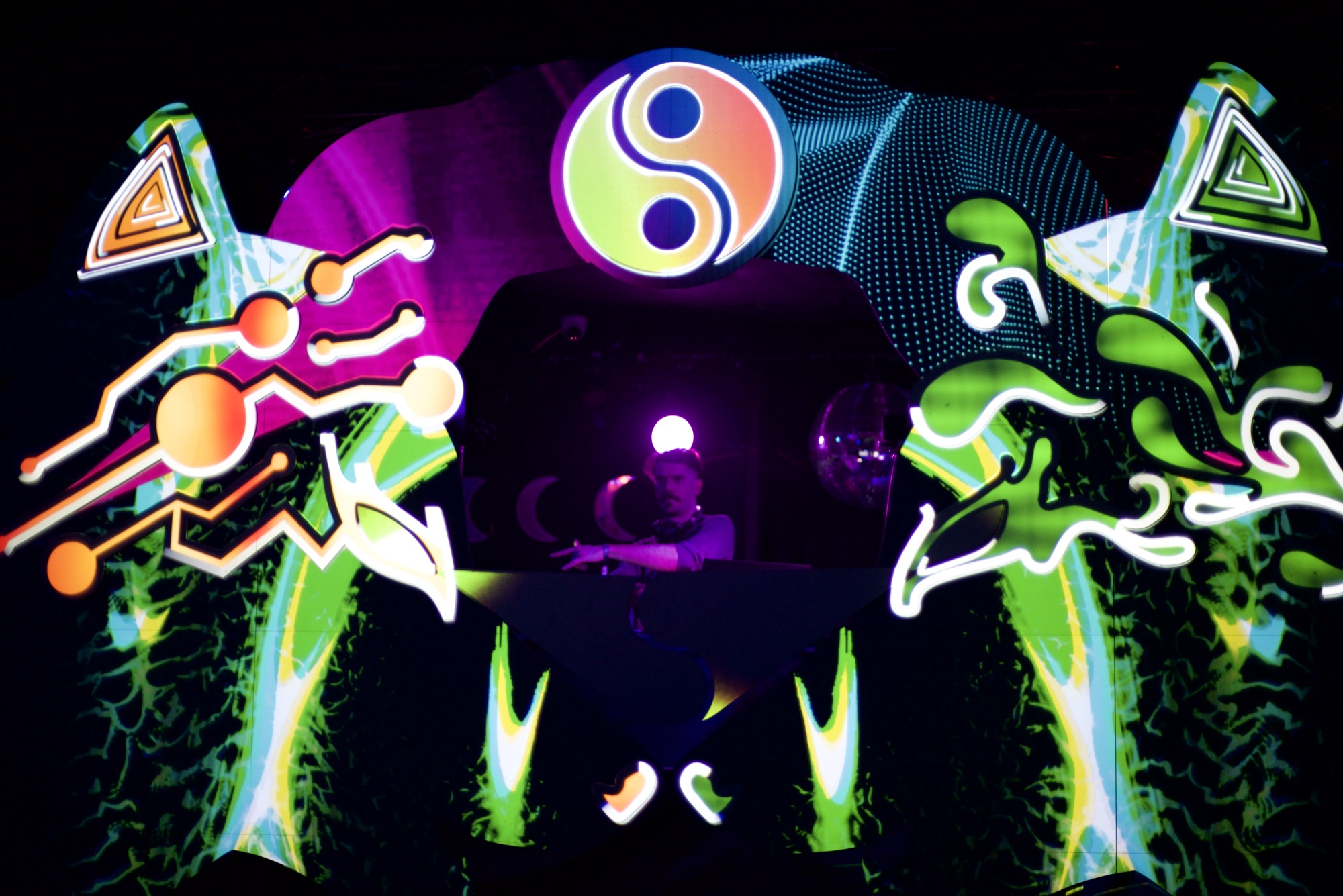 The Duality stage lit up in green and magenta, the DJ silhouetted beneath the yin-yang