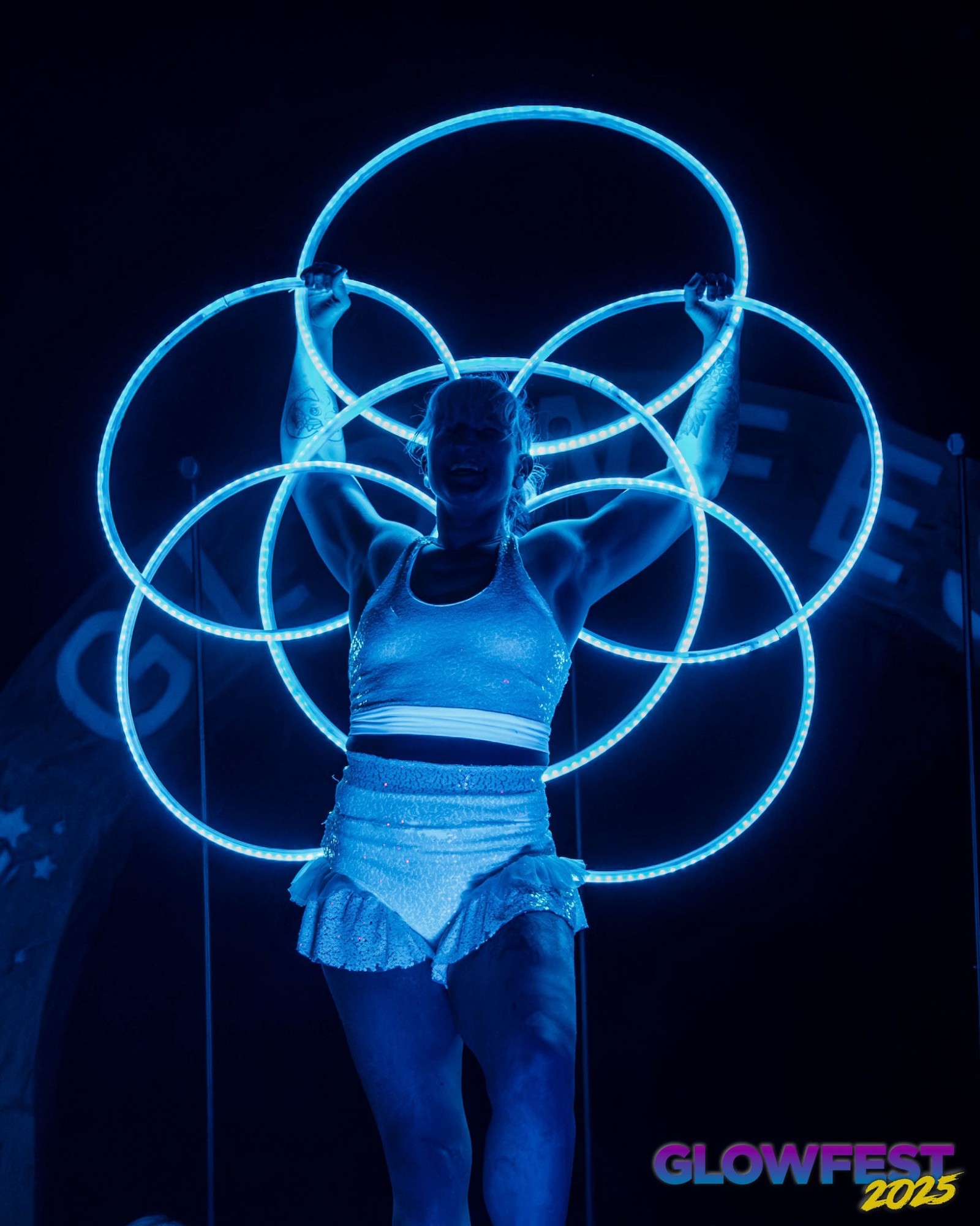 Jess holding six glowing blue hoops overhead, arranged into a flower shape