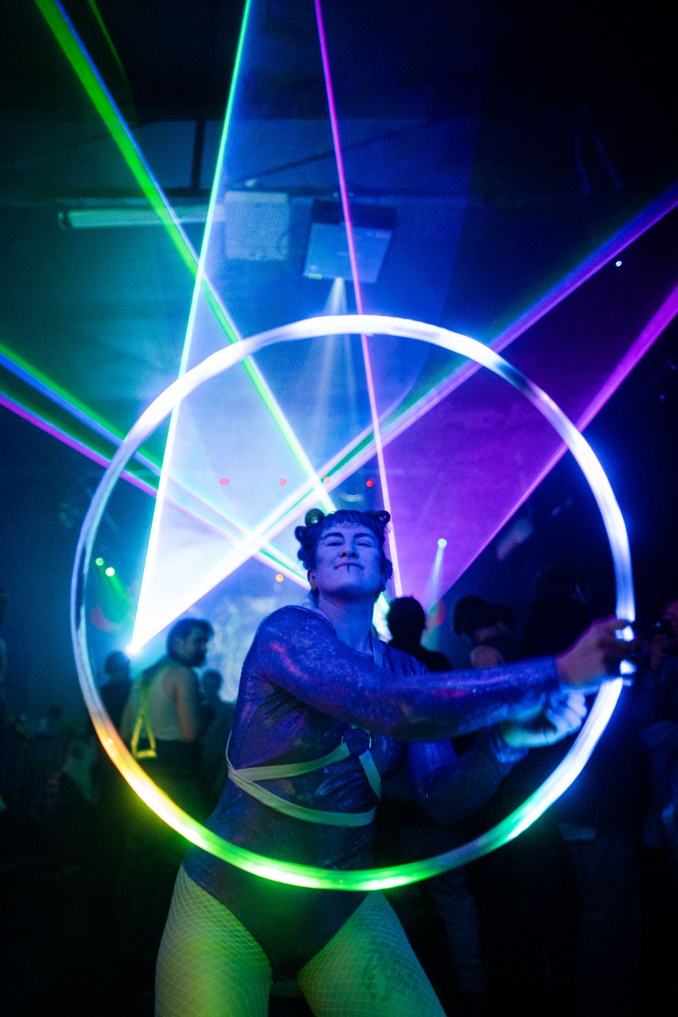 Jess spinning a glowing hoop through green and purple lasers on a dance floor
