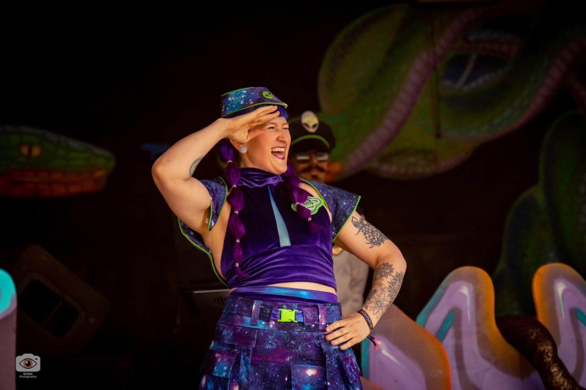 Jess laughing and saluting on stage in a handmade galaxy-print captain costume
